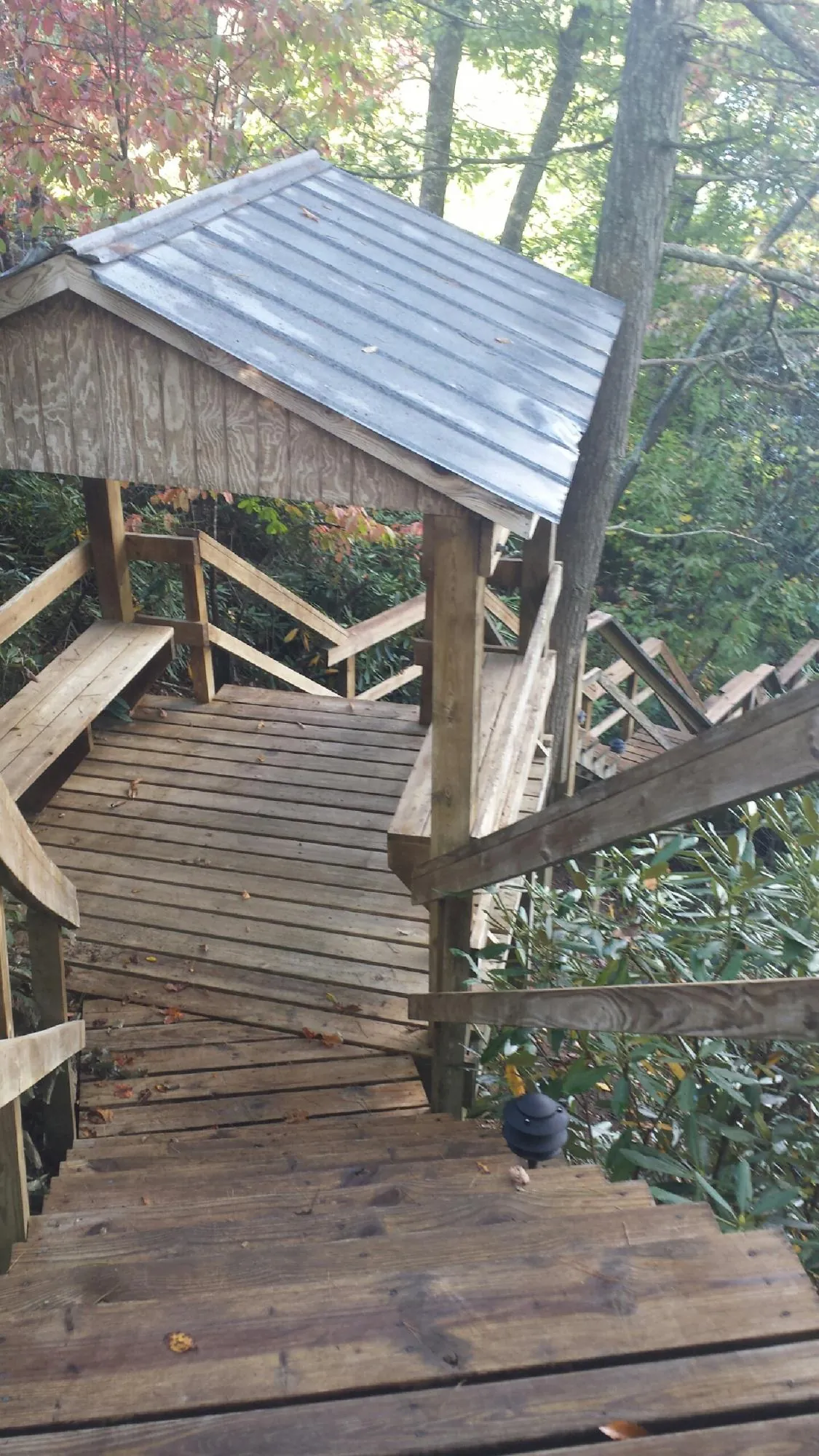 Metal roofed shelter over wooden steps on a wooded walkway — Skylight Repair & Installation work by our crew in Trenton